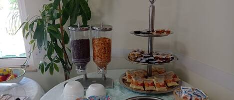 A buffet table with various food items, including trays of sandwiches, desserts, and packaged snacks.
