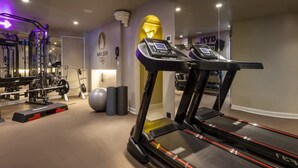 Un gimnasio con cintas de correr, máquinas de pesas y pelotas de ejercicio.