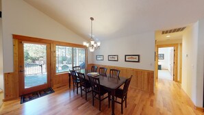 A dining room with a wooden table and chairs, a chandelier, and framed pictures on the wall. - Split Rock Hideaway with Access to Exclusive Golf (Sunriver)