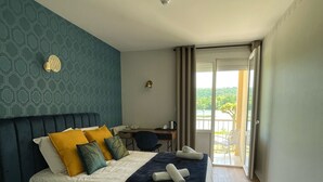 A hotel room with a bed, a desk, and a view of the outdoors. - Hôtel Restaurant du Lac (Boussens)