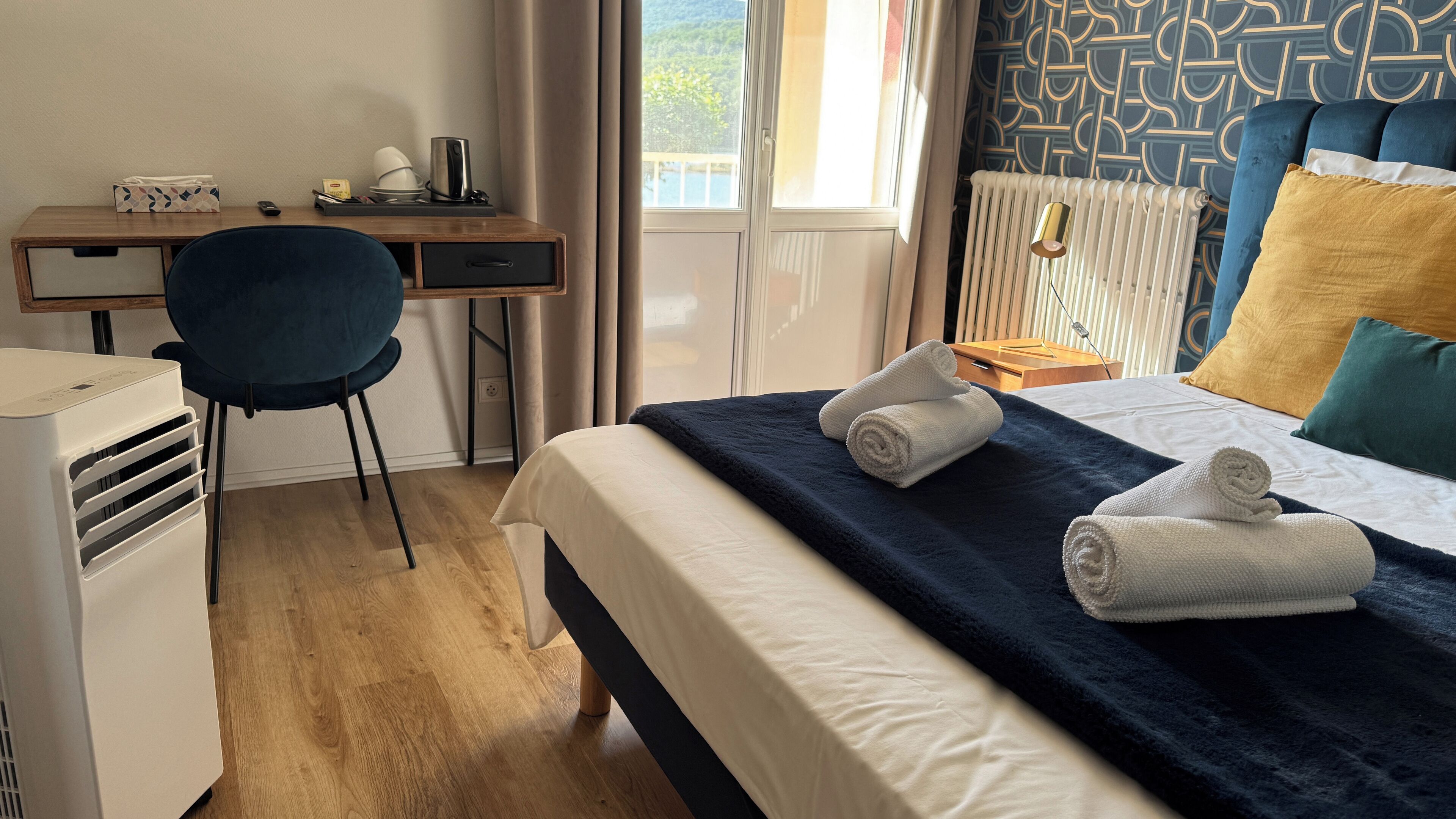Una habitación de hotel con una cama, un escritorio, una silla y un radiador.