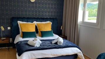 A neatly made bed with a dark blue headboard, white and yellow pillows, and a blue blanket.