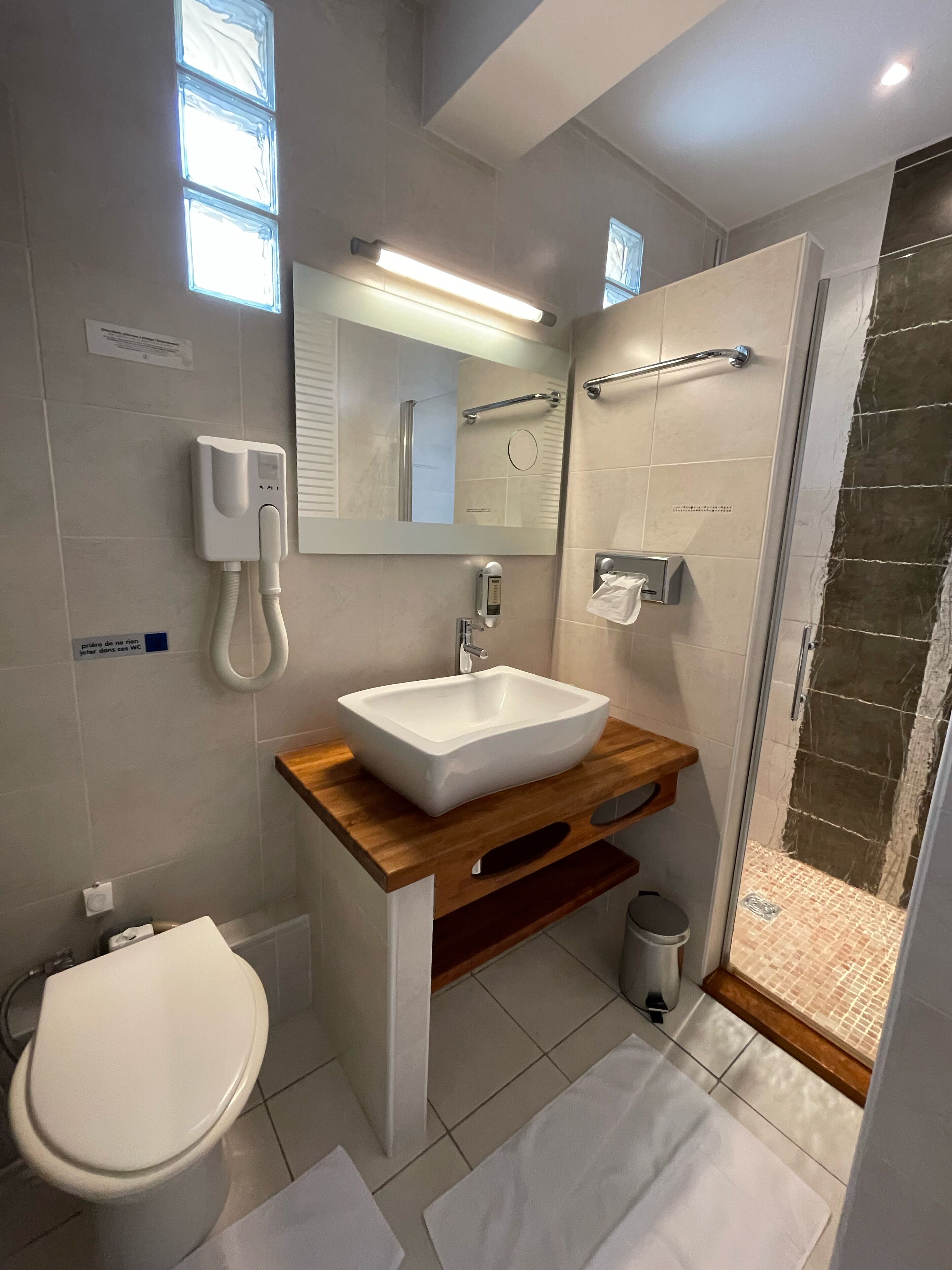A modern bathroom with a white sink, a toilet, a shower, and a mirror.