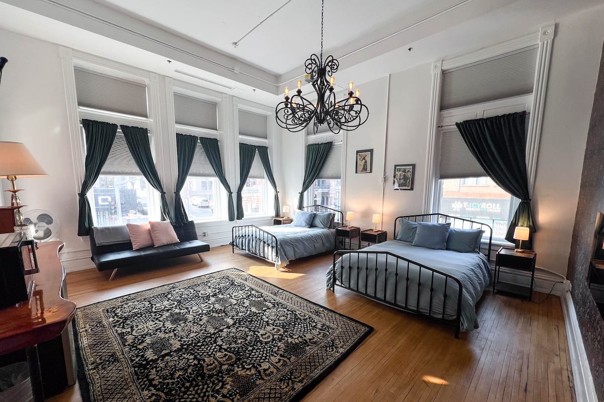 A spacious bedroom with a large bed, a smaller bed, a sofa, and a patterned rug.