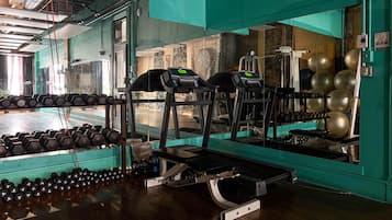 A gym with treadmills, dumbbells, and exercise balls.