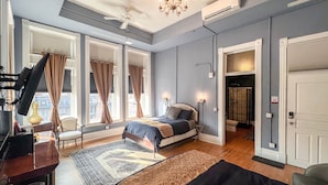 A bedroom with a bed, a desk, a chair, a rug, and a bookshelf. - The Oliver Inn | Duluth Hotel Near Canal Park (Duluth)