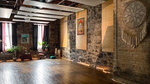 A spacious room with exposed brick walls, a wooden floor, and a large dreamcatcher hanging on the wall. - The Oliver Inn | Duluth Hotel Near Canal Park (Duluth)
