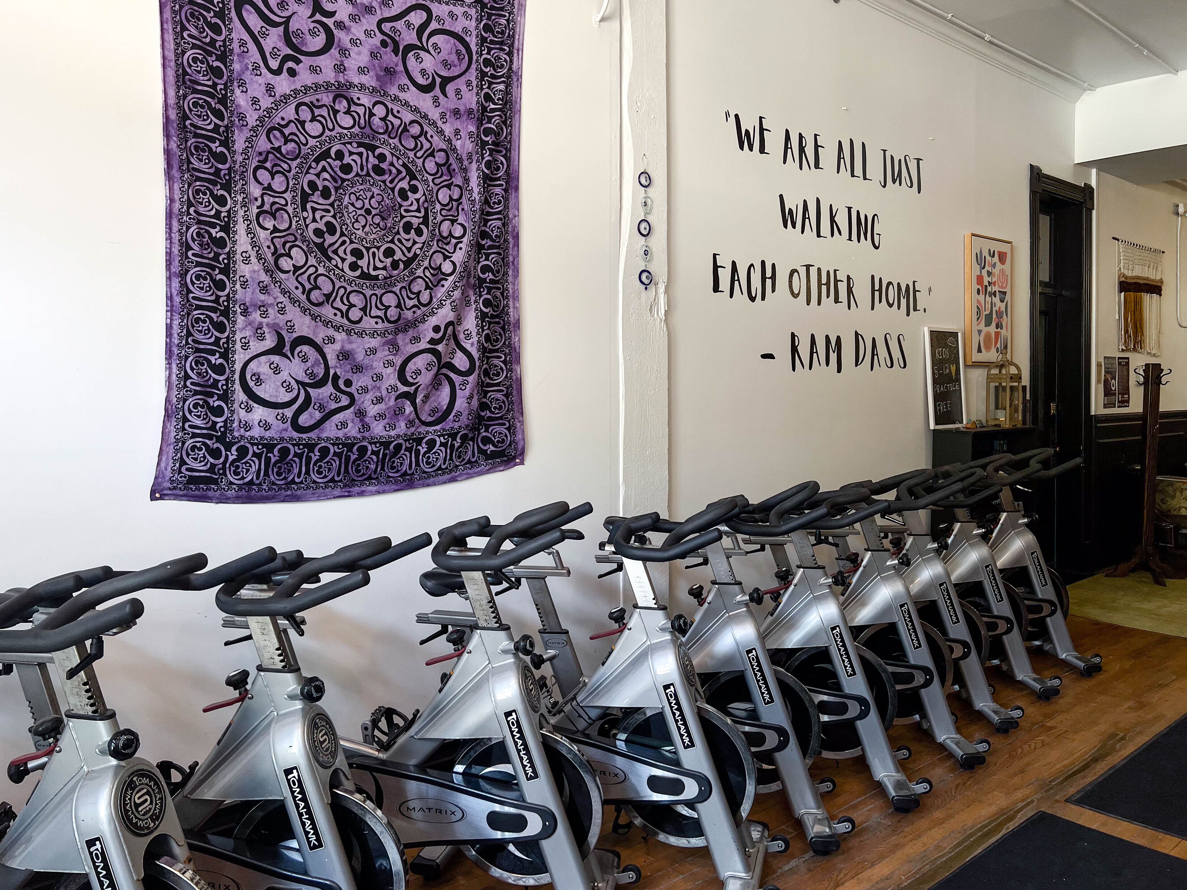 A row of stationary bikes in a room with a motivational quote on the wall.