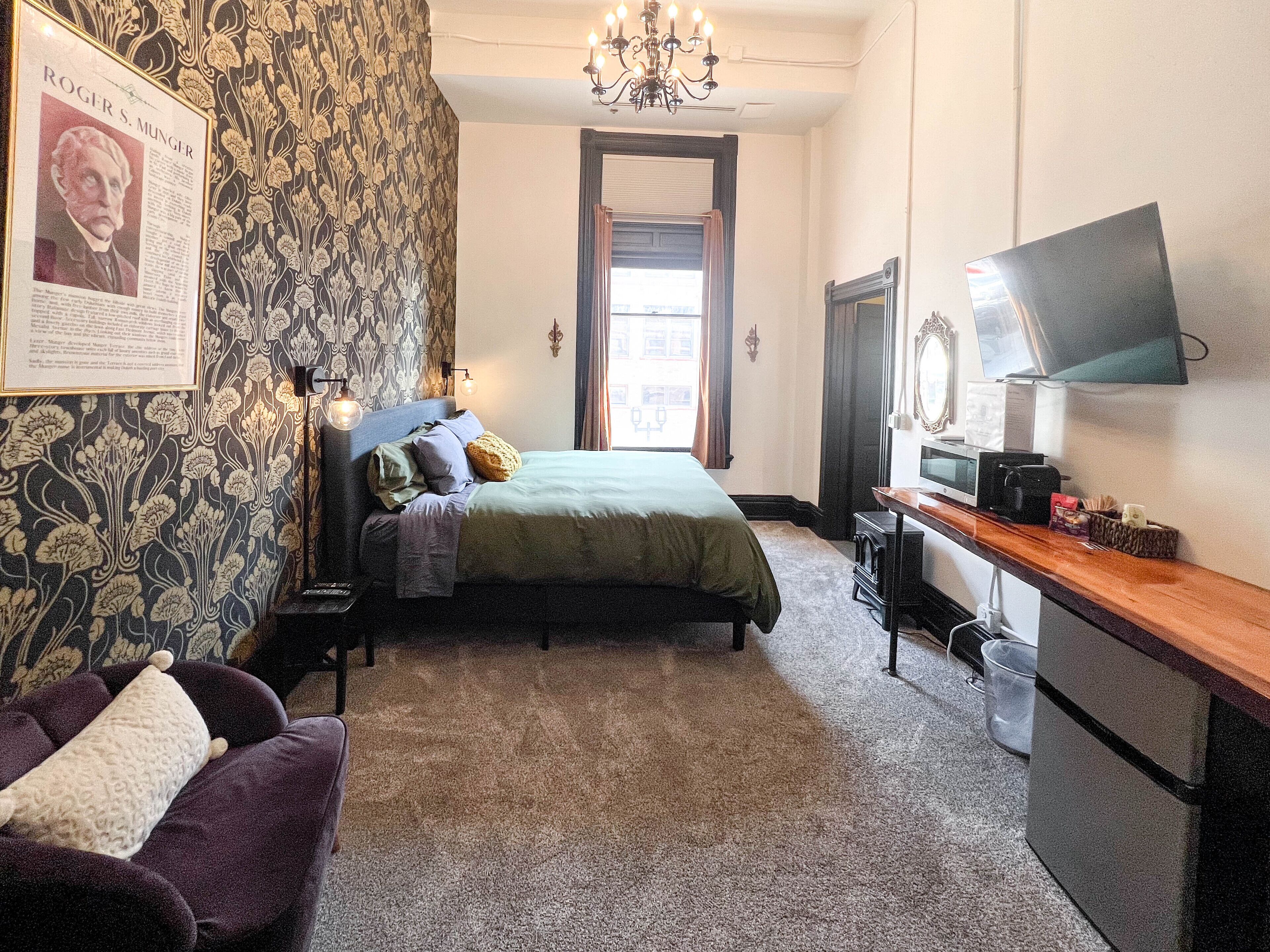 Een hotelkamer met een bed, een bureau met een computer, een televisie en een poster aan de muur.
