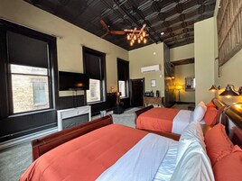 Una habitación de hotel con dos camas, televisor, escritorio y ventilador de techo.