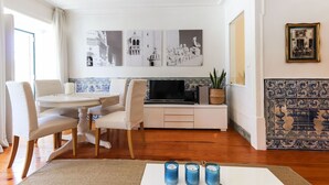 A living room with a dining area, a flat-screen TV, and wall-mounted artwork. - Belem Prestige by Homing (Lisbon)