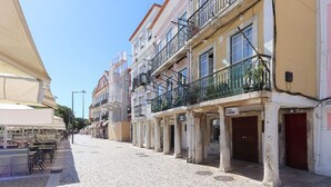 A cobblestone street lined with historic buildings, some with balconies and signage indicating local businesses. - Belem Prestige by Homing (Lisbon)