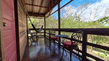 A covered outdoor seating area with a hammock, two chairs, and a table.