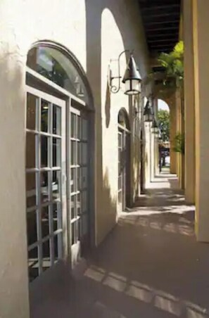 Stroll through a historic walkway lined with arches and columns, flanked by buildings with large windows and doors.
