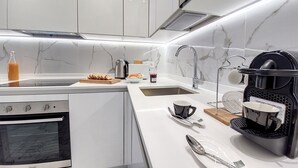 A modern kitchen with white cabinetry, a built-in oven, a coffee maker, and a sink. - N&J - FLOREAL BEACH - Central - Close sea  (Niza)