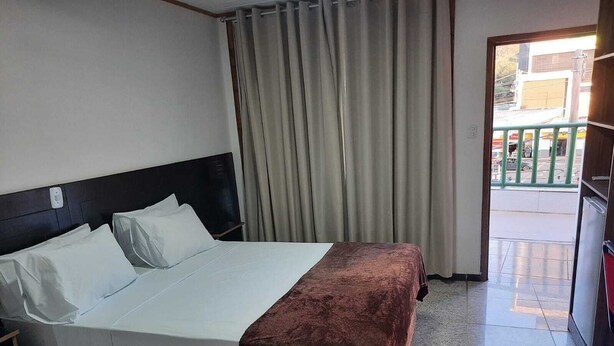 Una habitación de hotel con cama, cortinas y vistas al exterior.