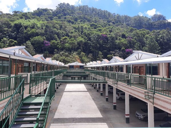 A hotel with multiple levels, connected by a central staircase, set against a backdrop of dense forest. - Hotel GH Express (Juiz de Fora)
