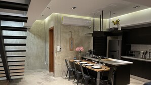 A modern kitchen with a central island, dark chairs, and a dining table set for four.