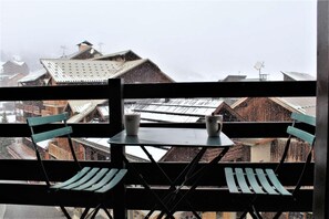 Relax on the balcony with a serene view of the snow-covered village below.