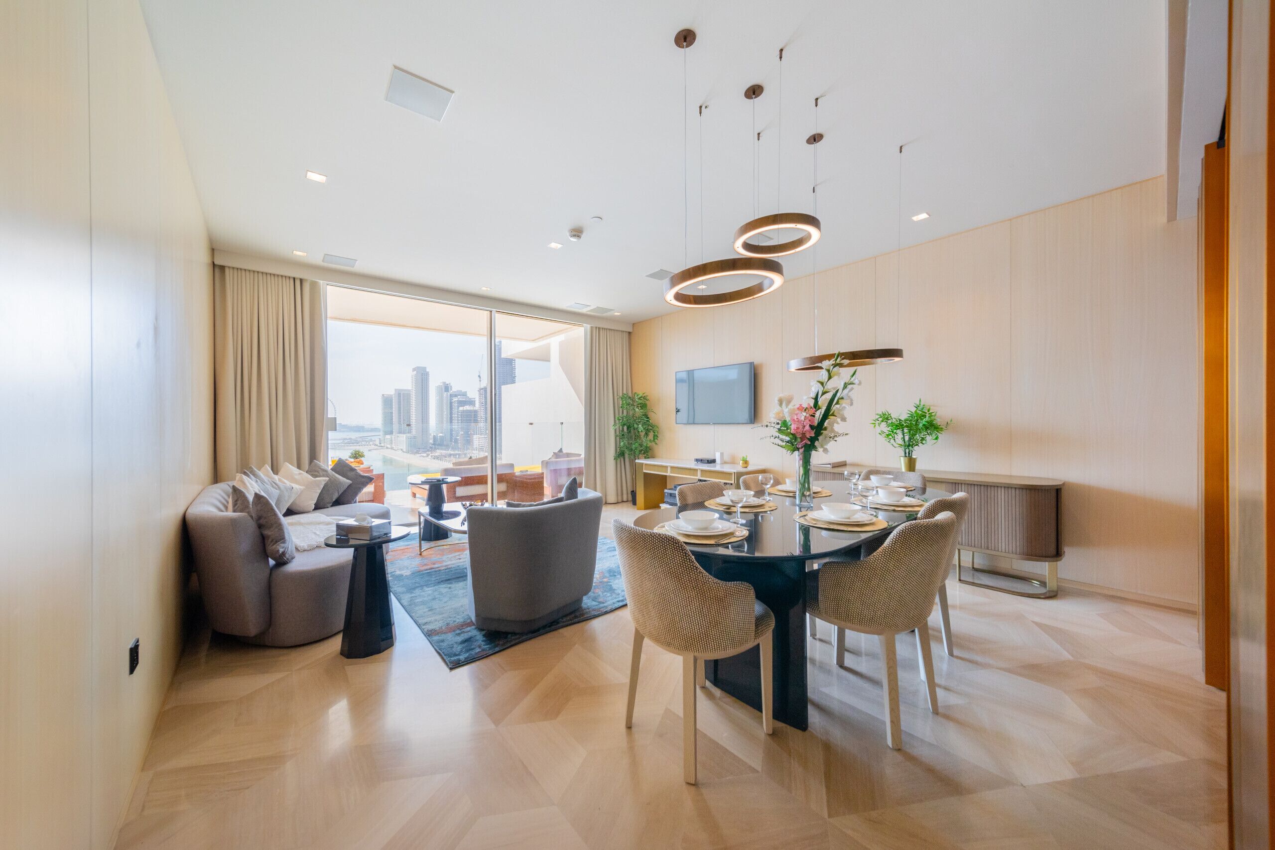 A modern living room with a dining area, large windows, and a city view.