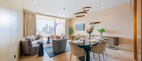 A modern living room with a dining area, large windows, and a city view.