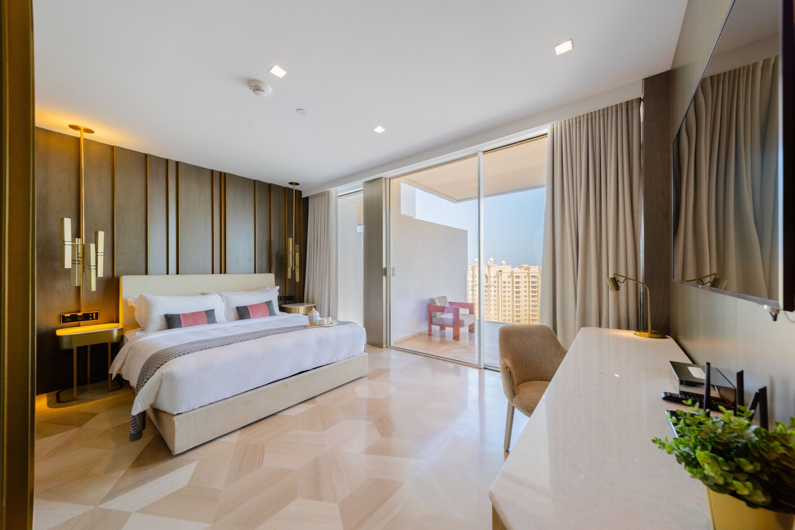 Ein modernes Hotelzimmer mit einem großen Bett, einem Schreibtisch und einem Balkon mit Blick auf die Stadt.