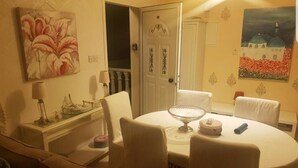 A dining area with a round table, chairs, a lamp, and a painting on the wall. - Nissi Villa Loreana (Ammochostos Ayia Napa)