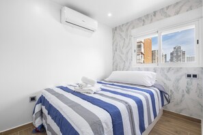 Quarto com cama, janela com vista para a cidade e ar condicionado.