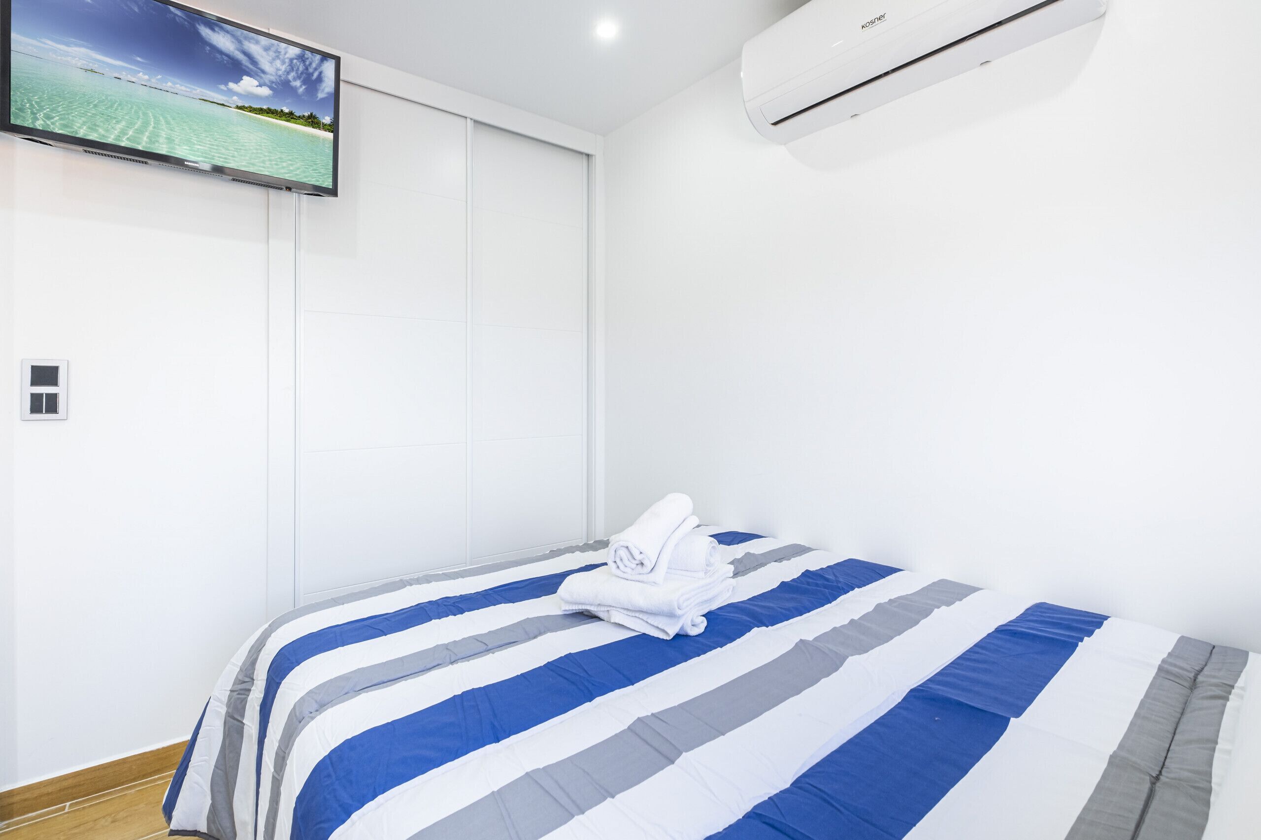 Ein Hotelzimmer mit einem Bett, einem Flachbildfernseher und einer Klimaanlage.
