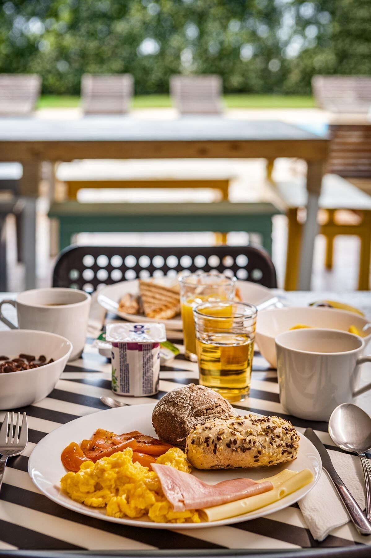 Uma mesa de café da manhã com ovos, bacon, torradas e suco.