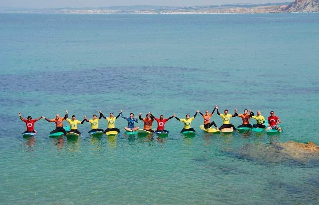 A group of people sitting on surfboards in the water.