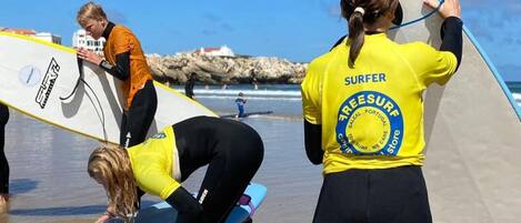 A beach scene with people in wetsuits preparing surfboards.