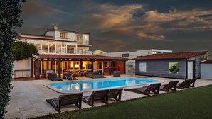 A modern house with a swimming pool, outdoor seating, and a well-maintained garden. - FreeSurfCamp (Peniche)