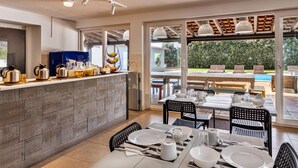A modern kitchen with a built-in island, a dining area with a view of the outdoors, and a poolside seating area. - FreeSurfCamp (Peniche)