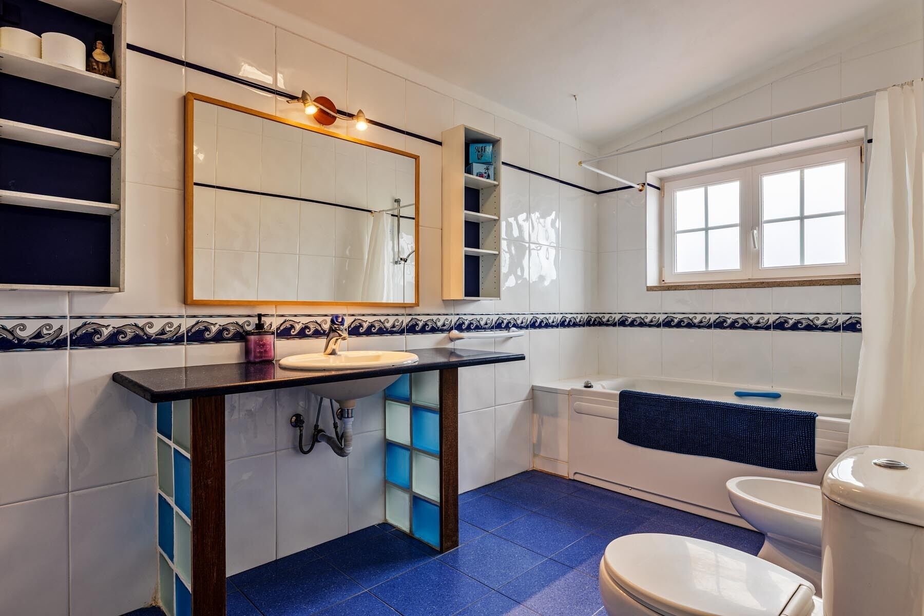 Ein Badezimmer mit Waschbecken, Spiegel, Dusche und Toilette.