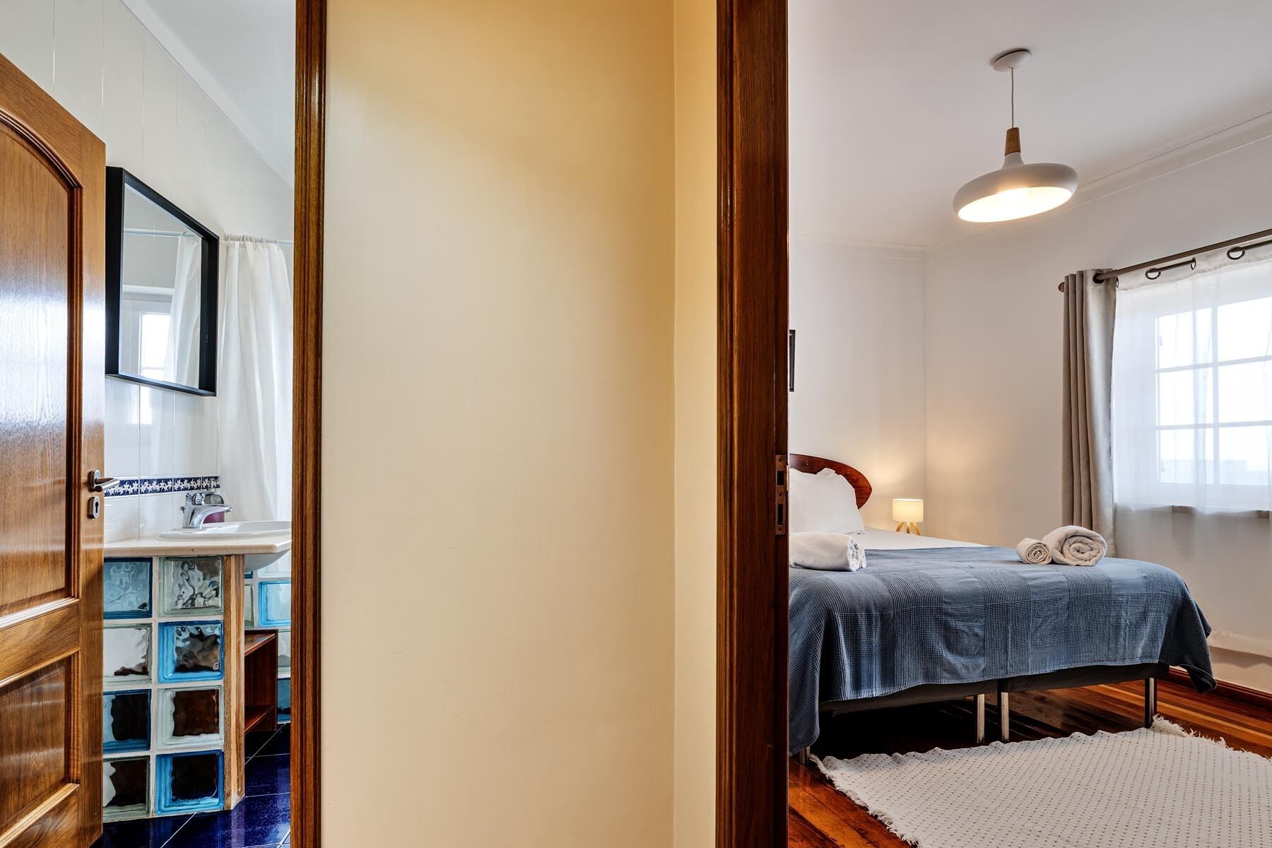 A bedroom with a bed, bedside lamp, and a window with curtains.