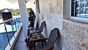 Ein Balkon mit zwei Holzstühlen, einem kleinen Tisch und einem Grill.