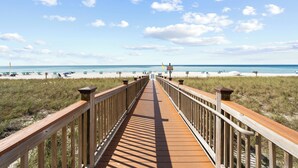 A wooden boardwalk leading to a beach with clear skies and a few clouds. - Beach Colony E10B (Pensacola)