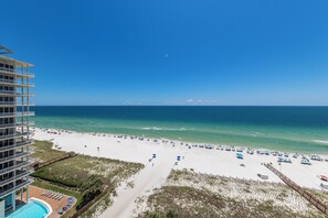 A beach view from a high-rise building with a pool and beach umbrellas. - Beach Colony E10B (Pensacola)