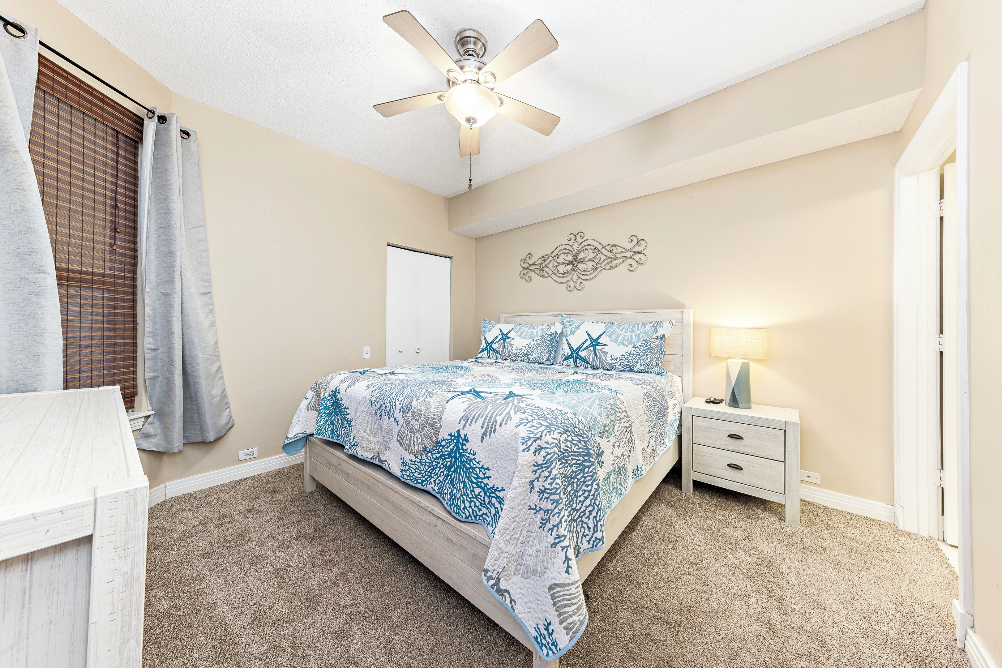 A bedroom with a bed, a nightstand, a ceiling fan, and a window with blinds.
