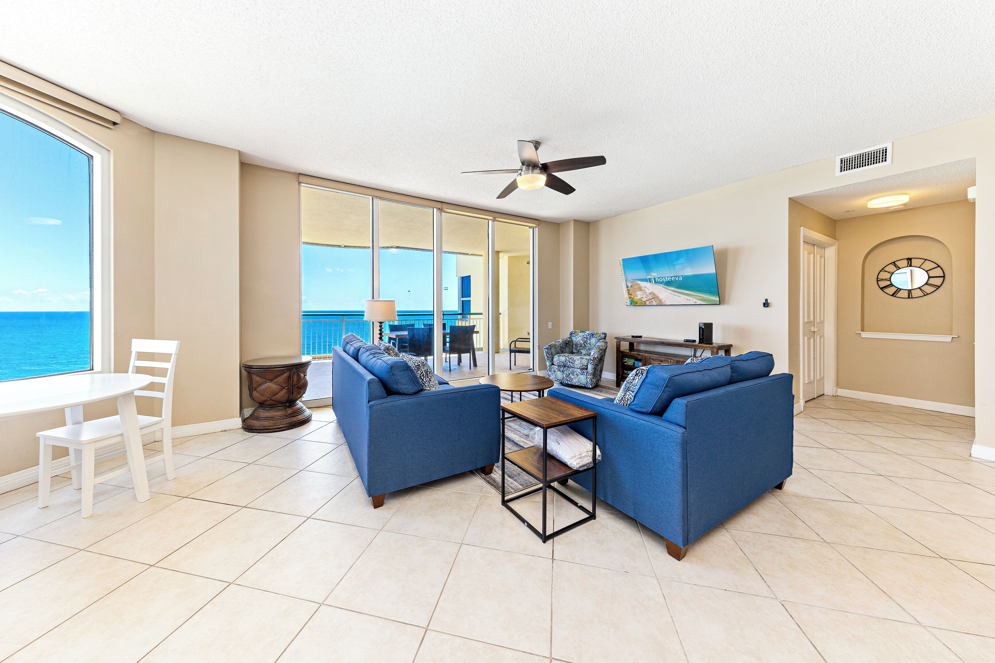 A spacious living area with a large window, a ceiling fan, and a view of the ocean.