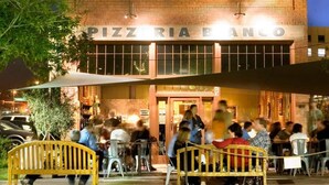 Un bâtiment en briques sur lequel on peut lire, la nuit, une enseigne indiquant « PIZZERIA BANCO ».