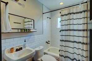 Ein Badezimmer mit Waschbecken, Toilette, Badewanne, Spiegel und Duschvorhang.