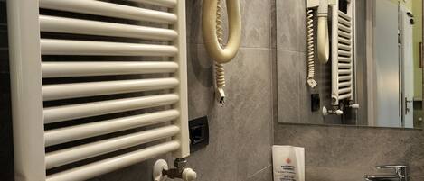 Ein Badezimmer mit weißem Heizkörper, Waschbecken und Spiegel sowie einem Handtuchhalter.