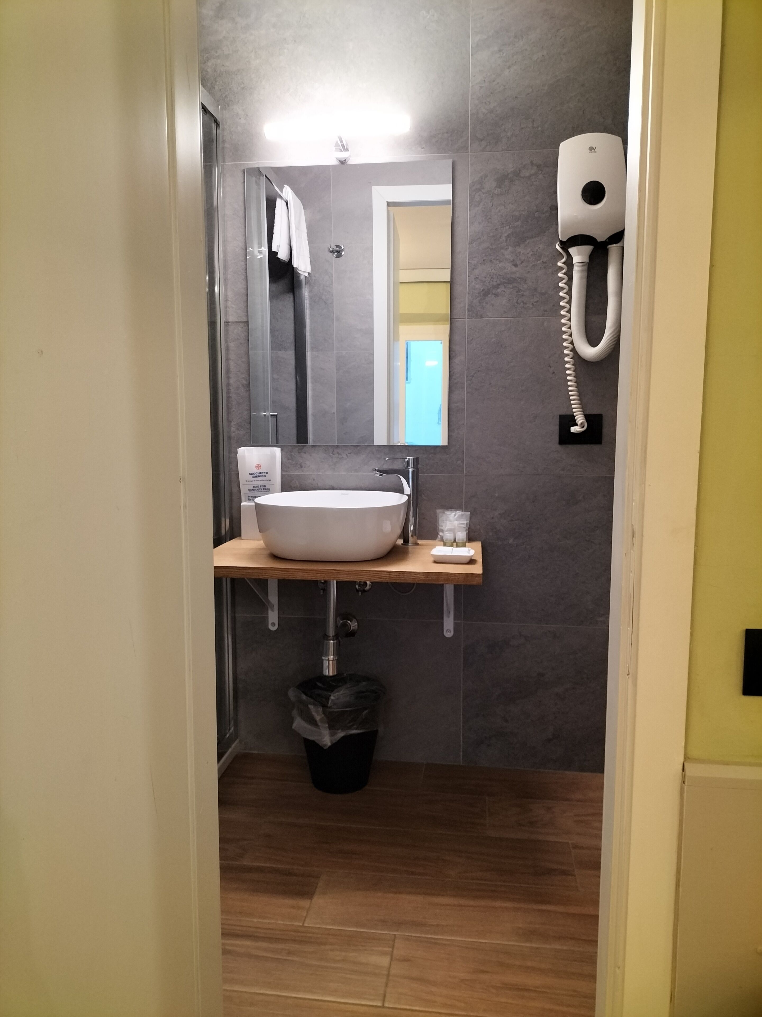 A modern bathroom with a large white sink, a mirror, and a hand dryer.