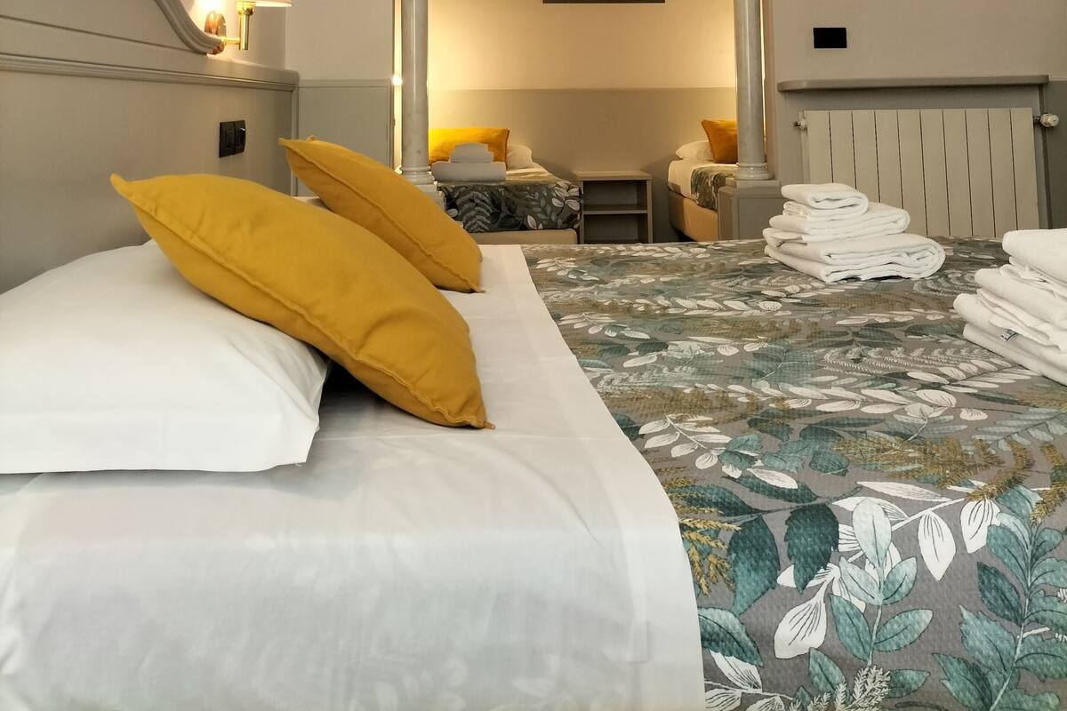A hotel room with a large bed, a smaller bed, a sitting area, and a painting on the wall.