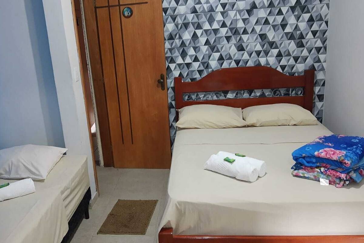 Une chambre avec deux lits, une porte en bois et un mur orné de motifs.