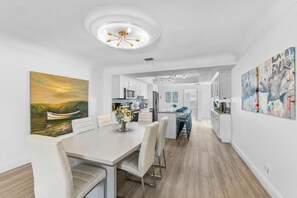 Enjoy meals in the dining area with a long table and comfortable chairs, surrounded by a vase with fresh flowers.