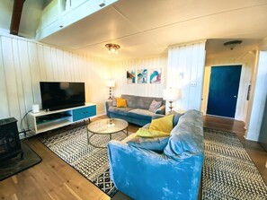 Ein Wohnzimmer mit Fernseher, Sofa, Couchtisch und gemusterten Teppichen.