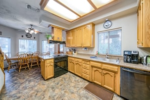 A kitchen with wooden cabinets, a stove, a sink, and a clock on the wall.